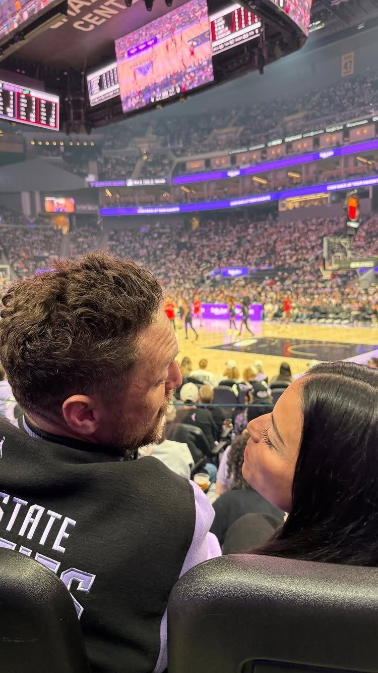 Couple looking at each other while attending a professional basketball game in an arena.