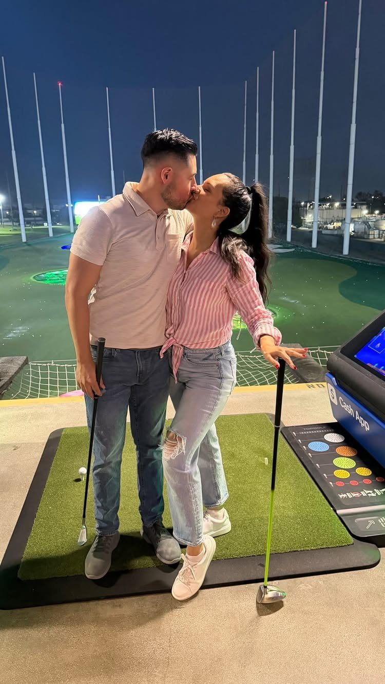 Couple kissing at a golf driving range during a night date.