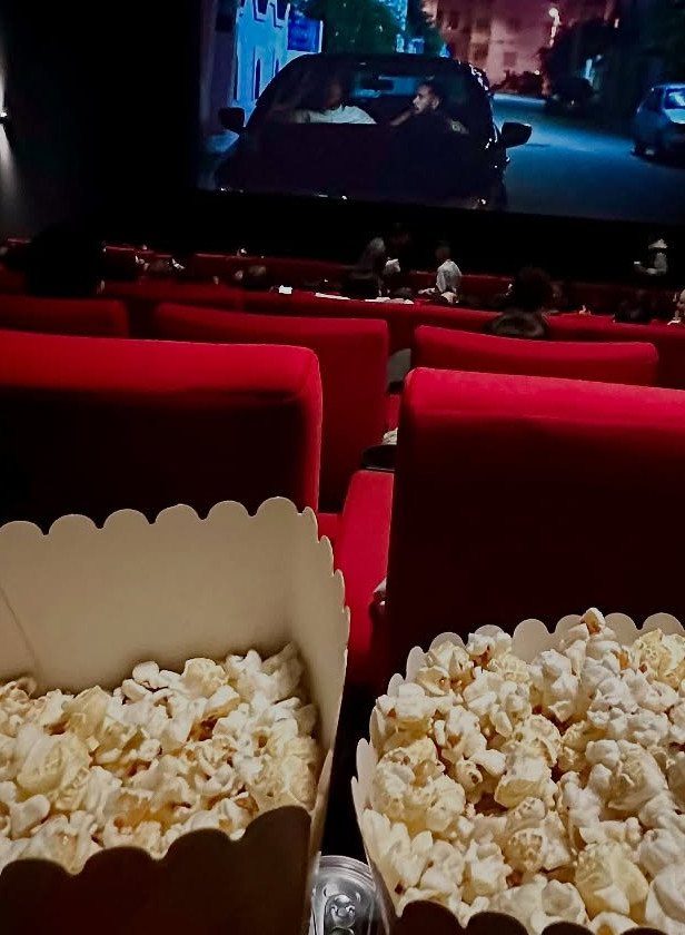 Popcorn buckets in a movie theater with a film playing on the screen