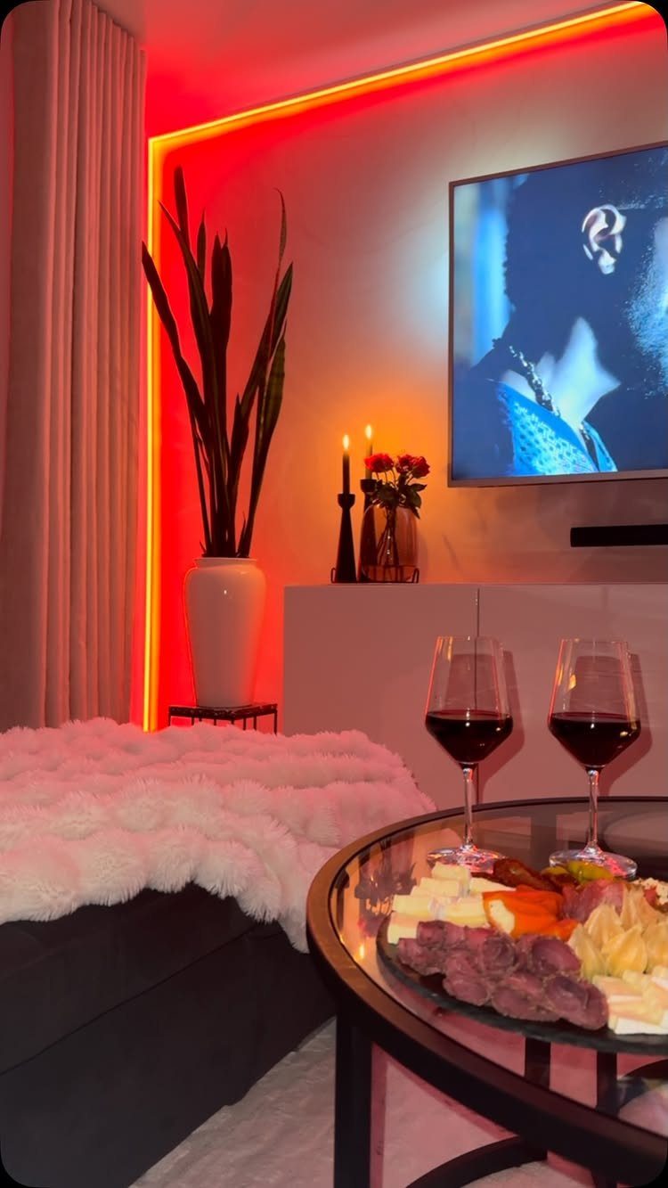 Two glasses of red wine and charcuterie on a table in a romantic room.