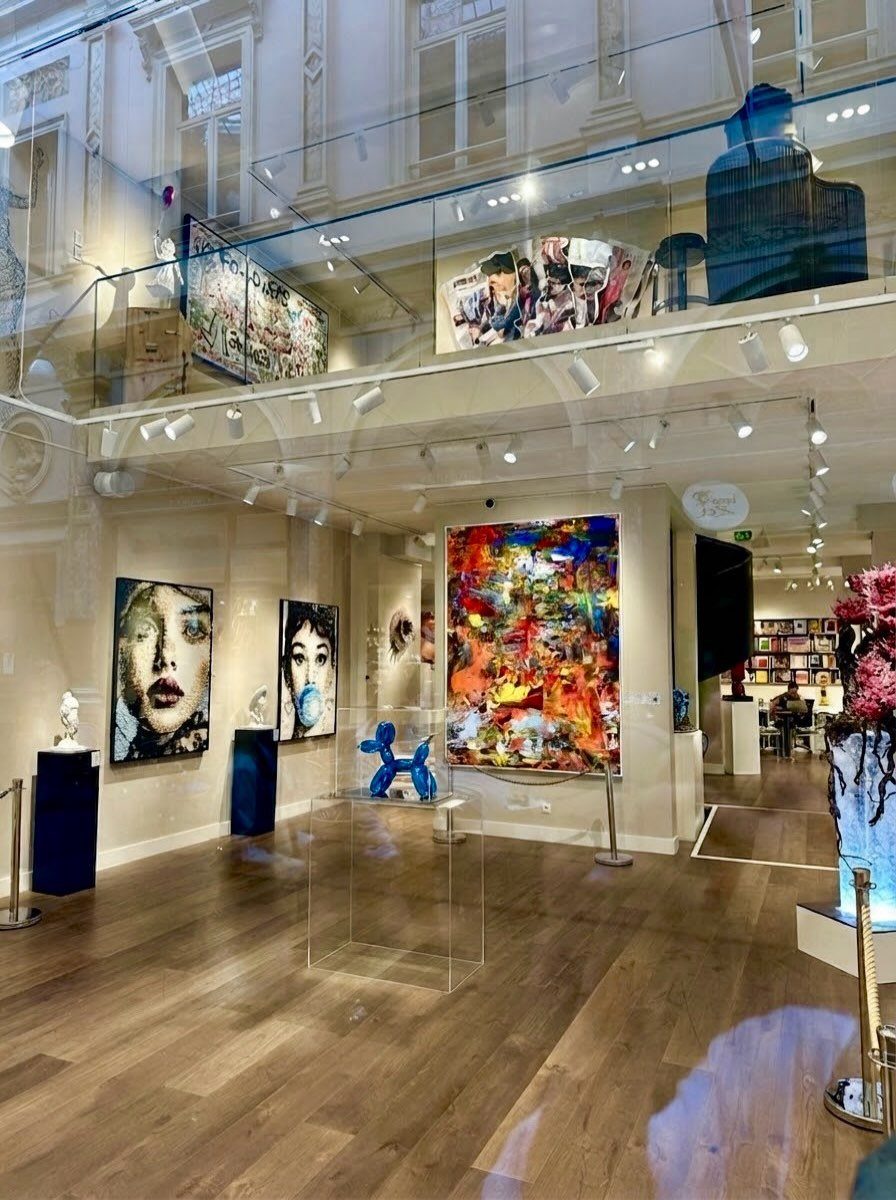 Modern art gallery interior featuring colorful paintings and blue sculptures on hardwood floors.