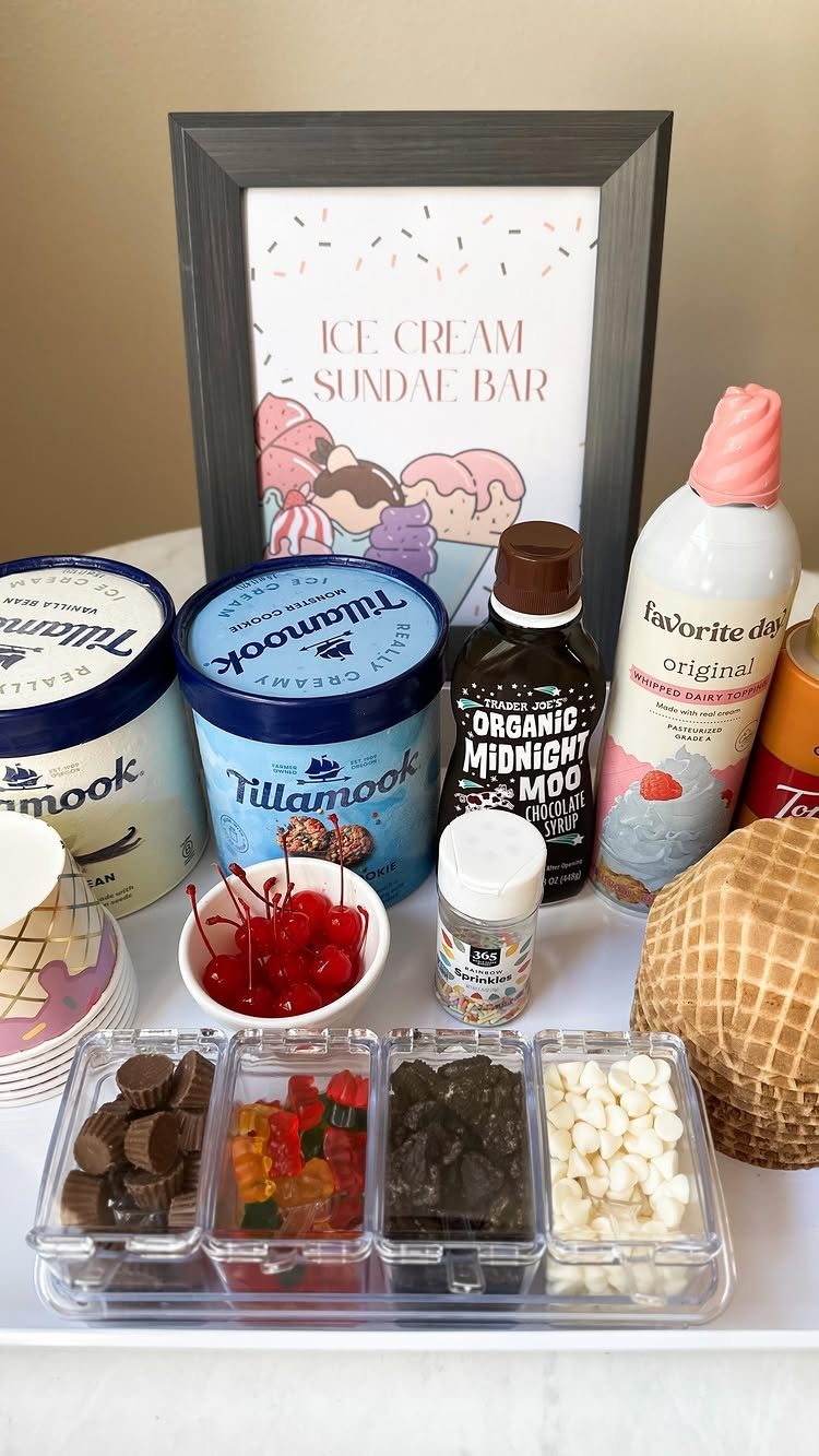 Ice cream sundae bar with pints, toppings, waffle cones, and a framed sign.