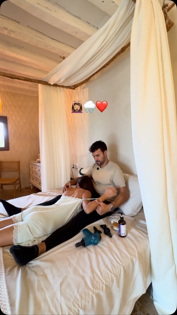 Man giving a massage to a woman on a bed with massage tools.