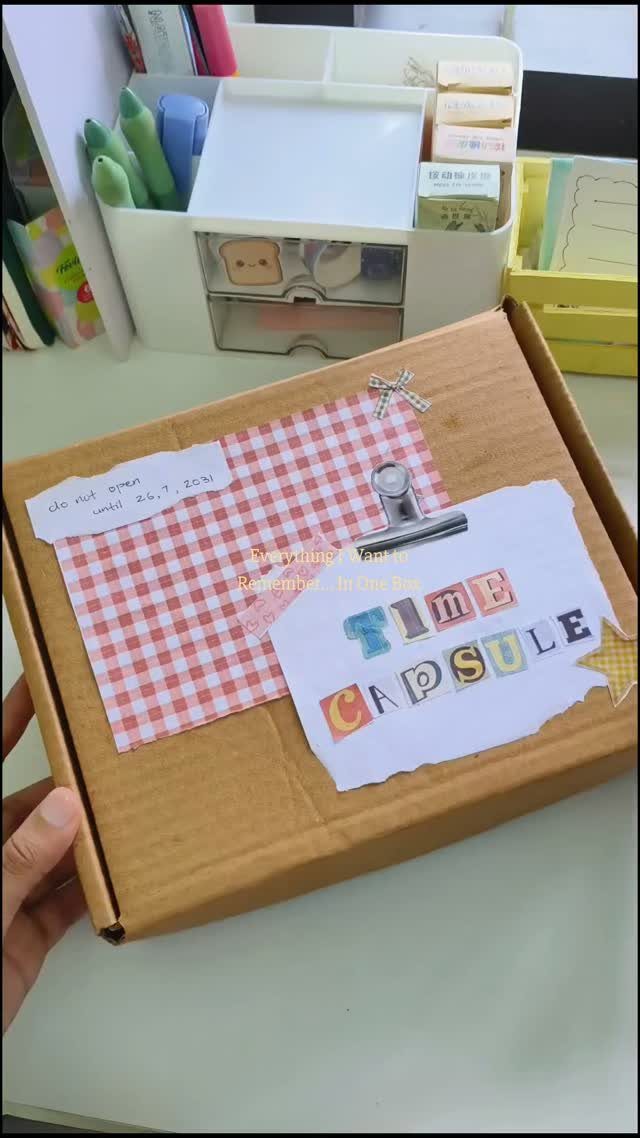Cardboard box decorated as a time capsule sitting on a white desk.
