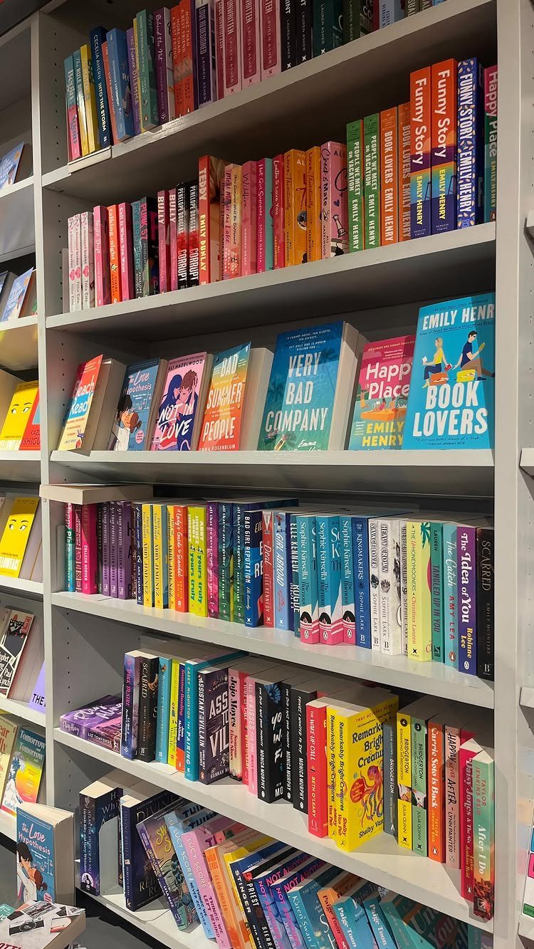 Colorful books arranged on white shelves in a bookstore with some covers facing forward.
