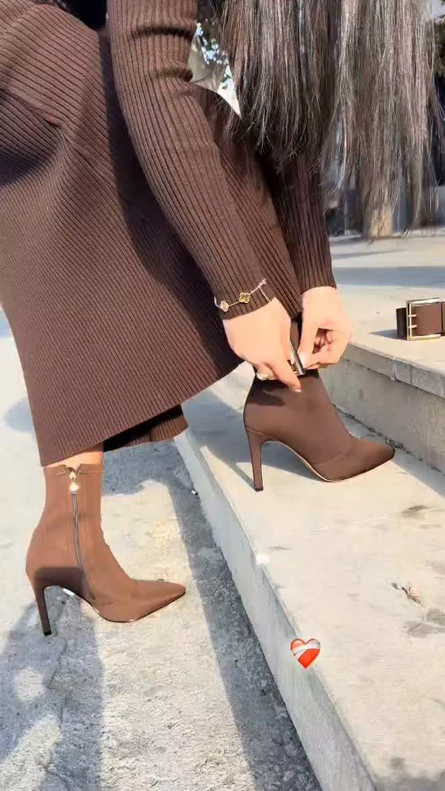 Brown pointed-toe heeled ankle boots worn with a brown ribbed knit dress.