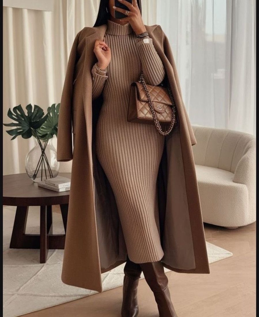 Woman in tan ribbed knit dress and long coat with brown leather boots.