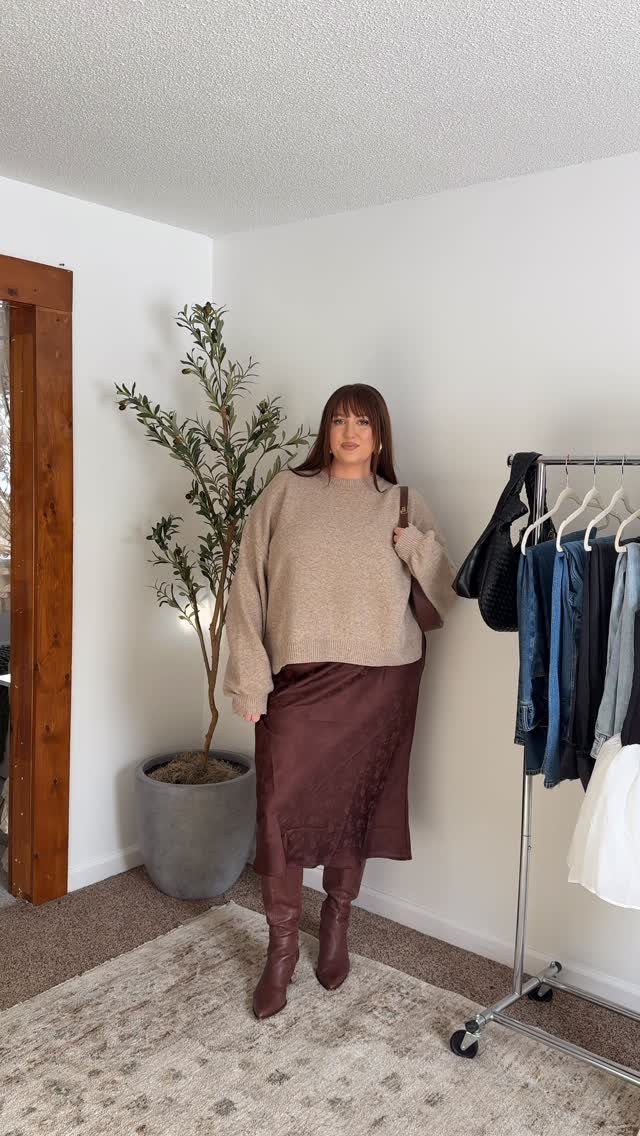 Woman wearing a beige sweater, brown satin skirt, and brown knee-high boots.