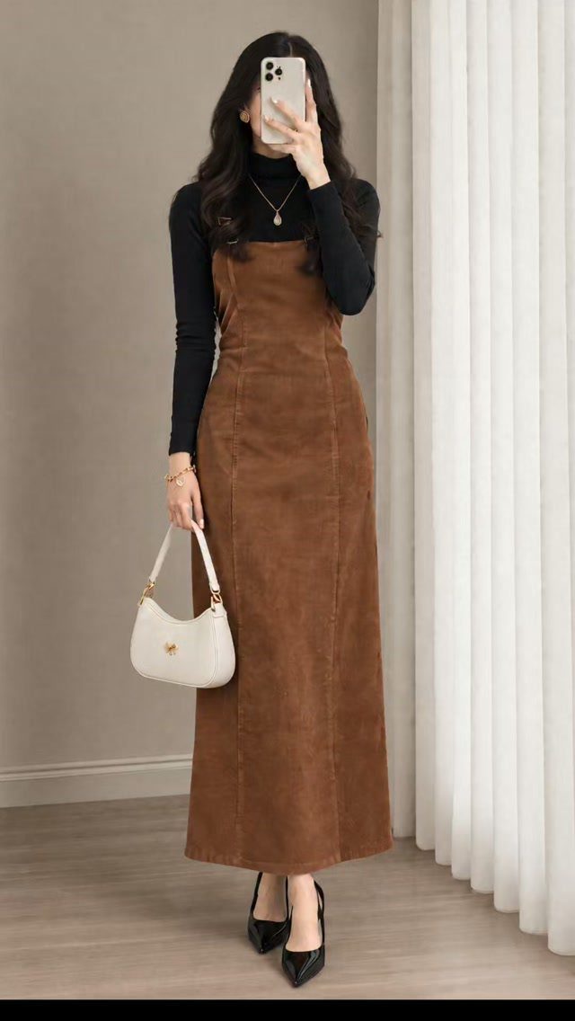 Woman wearing a brown corduroy pinafore dress over a black turtleneck with heels.