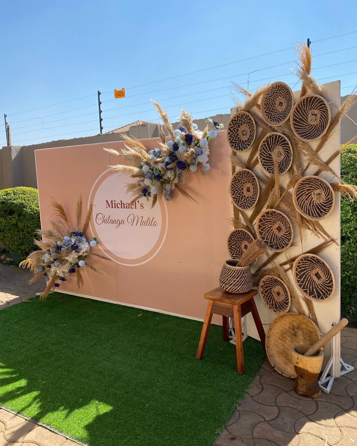 Peach backdrop with floral arrangements and woven baskets for a photo booth setup.