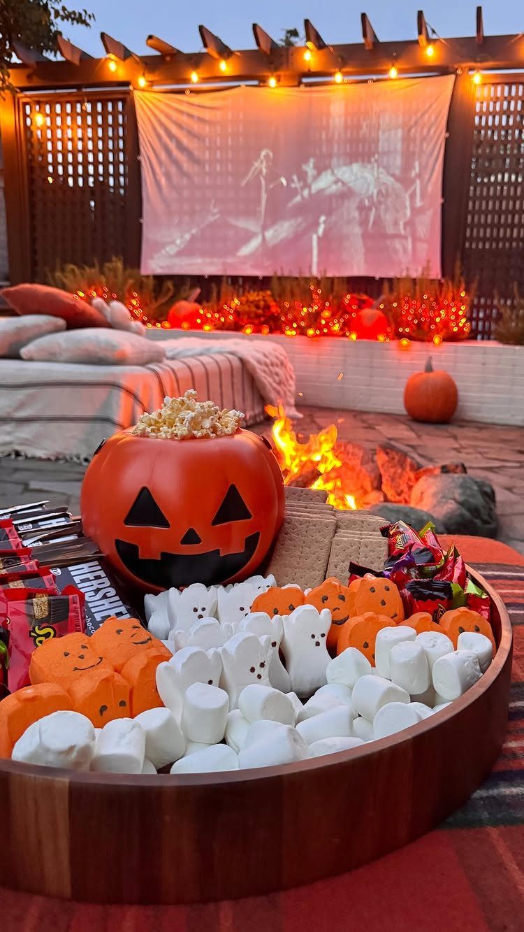 Outdoor movie night setup with a fire pit, snacks, and a projector screen.