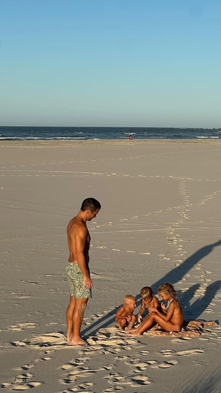 Father and three young children spending time together on a sunny sandy beach