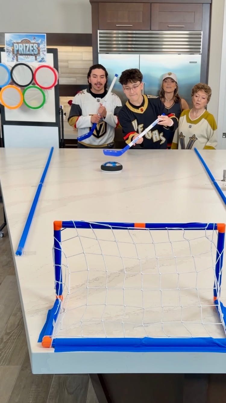 People playing miniature table hockey with a small net and Olympic prizes sign.