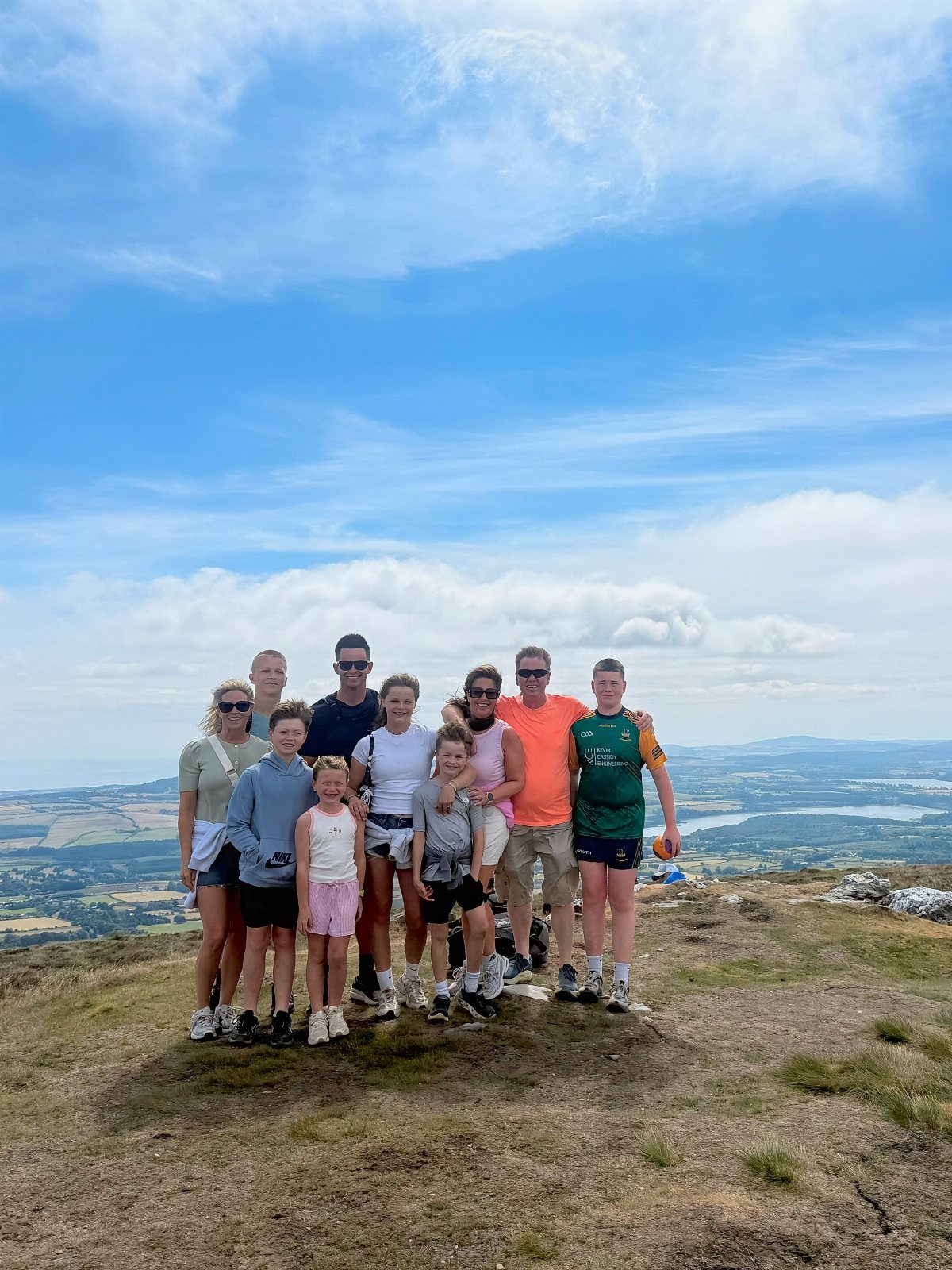 Group of people in athletic wear posing on a hilltop overlooking a valley.