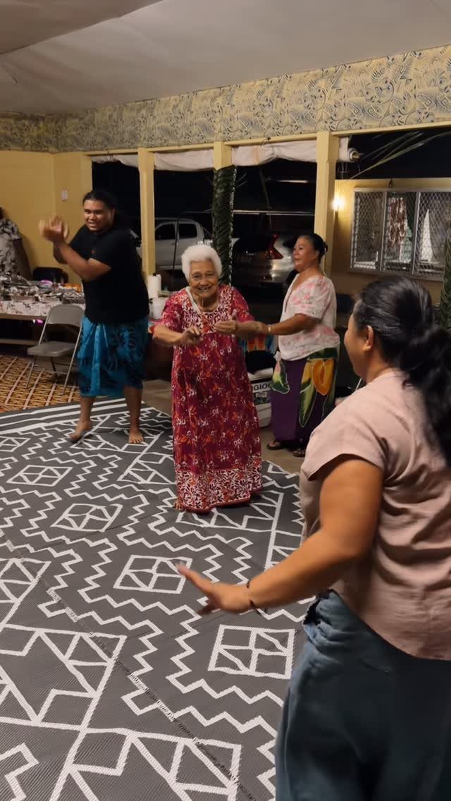 Multi-generational family dancing together on a patterned mat in a home setting.