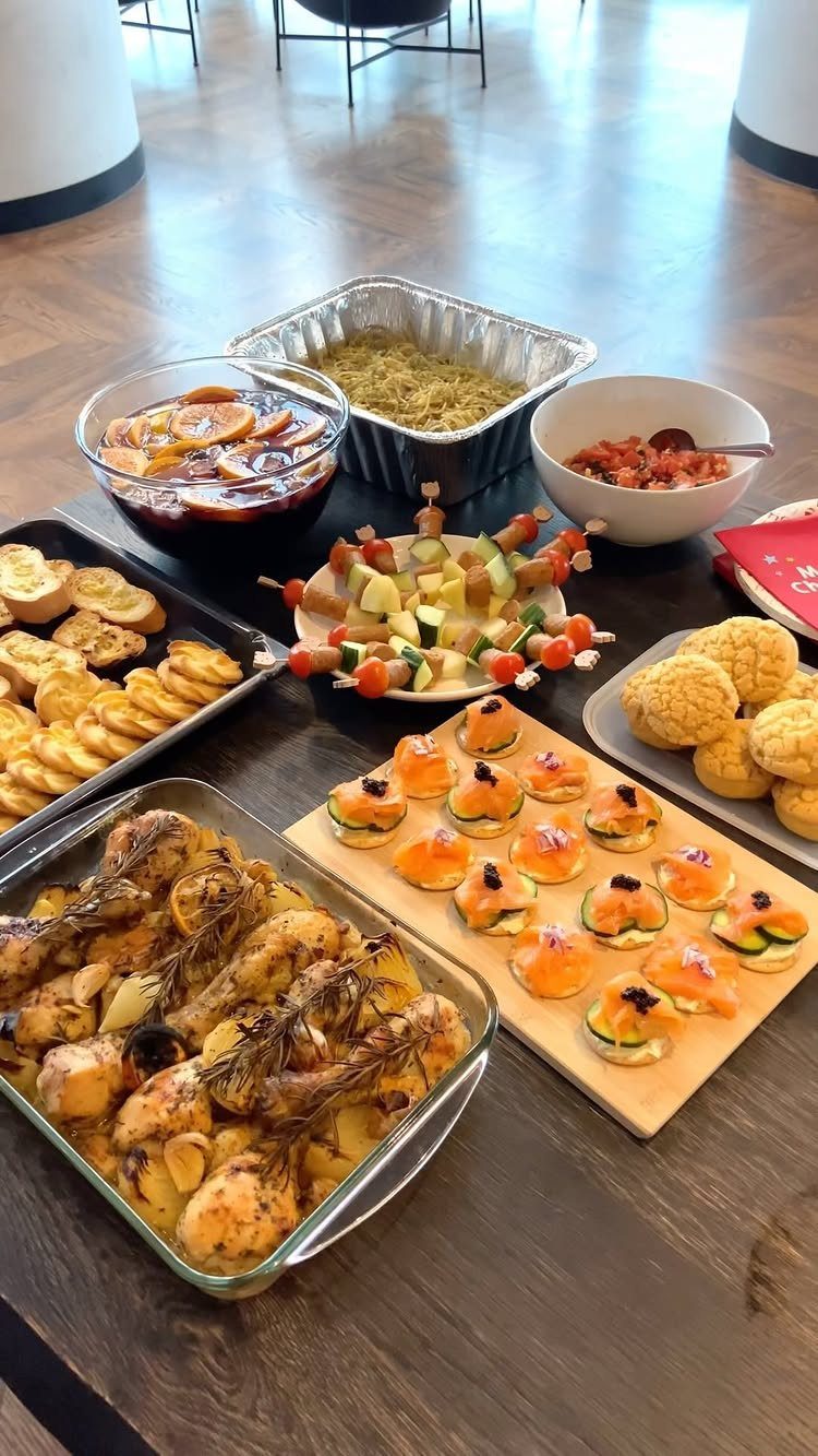 Assorted party appetizers and main dishes spread across a dark wooden table.