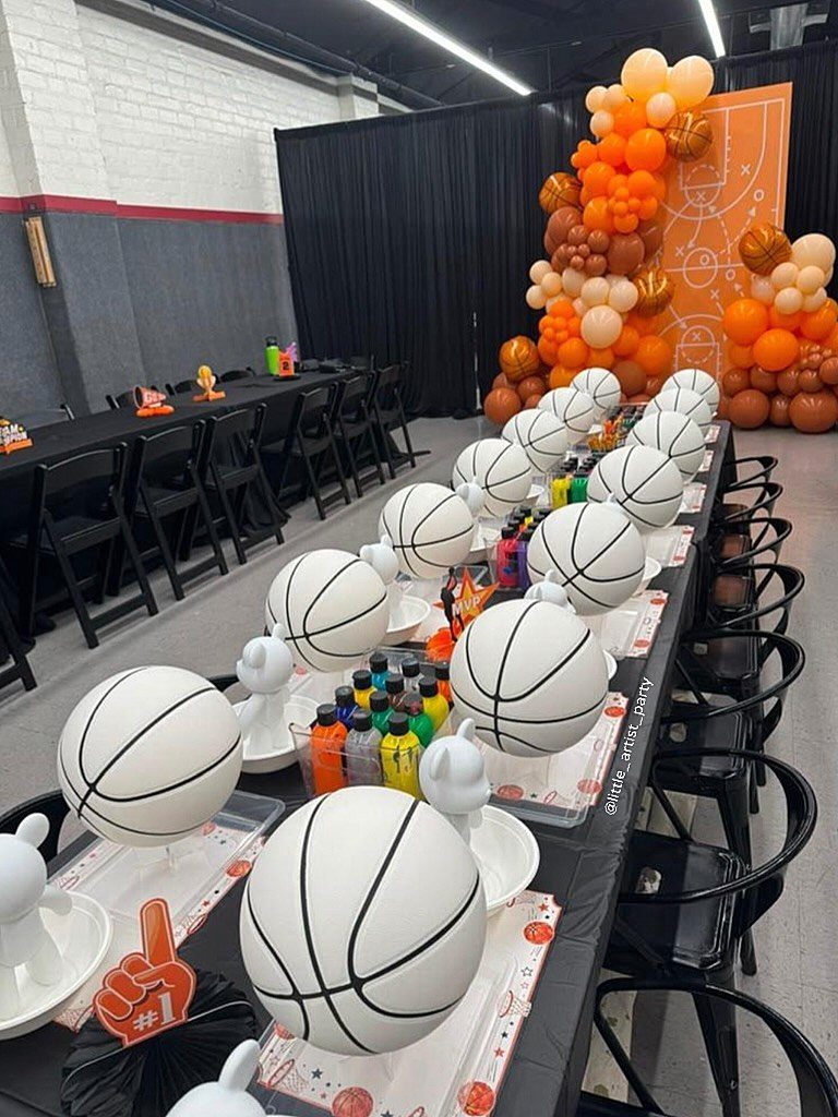 Basketball themed party table with basketball cake pops and orange balloon arch.