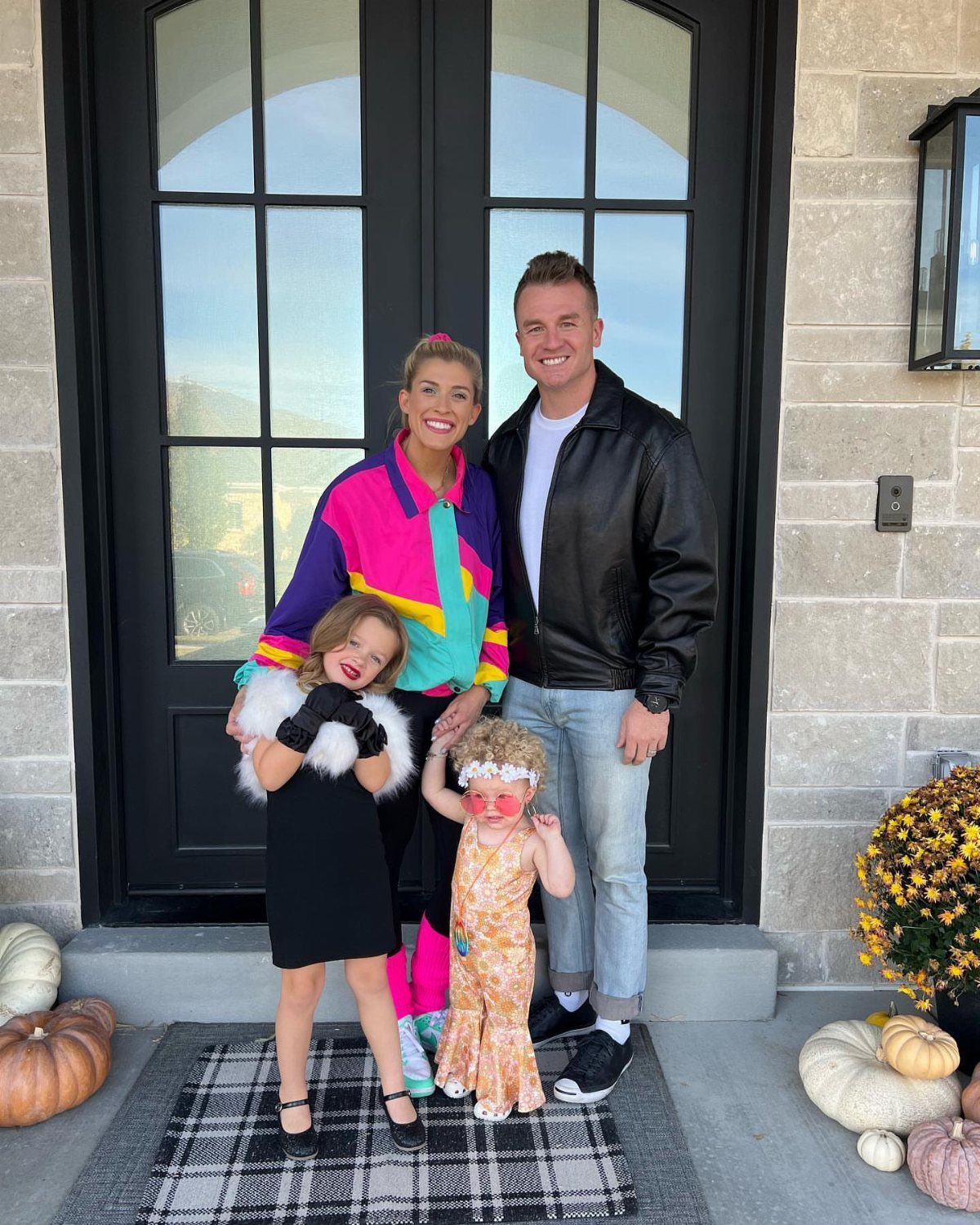 Family of four wearing costumes from different decades posing in front of a house.