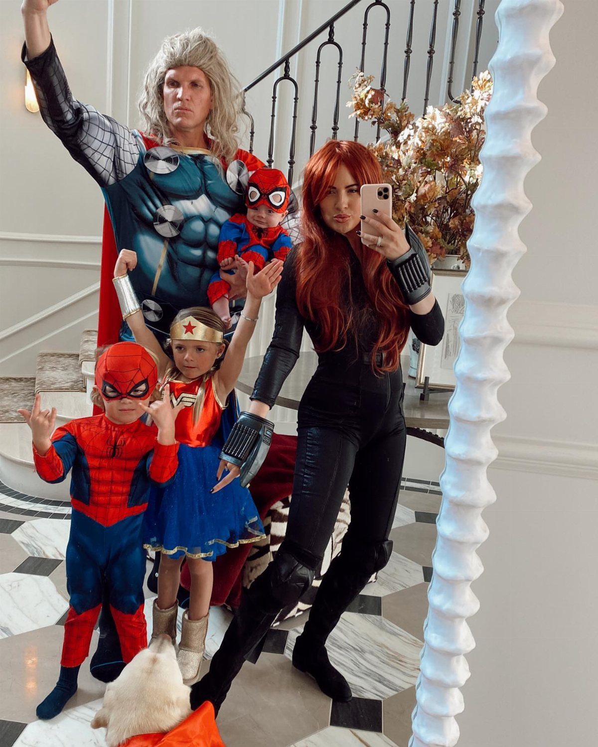 Family wearing superhero costumes including Thor and Spider-Man posing for a mirror selfie.
