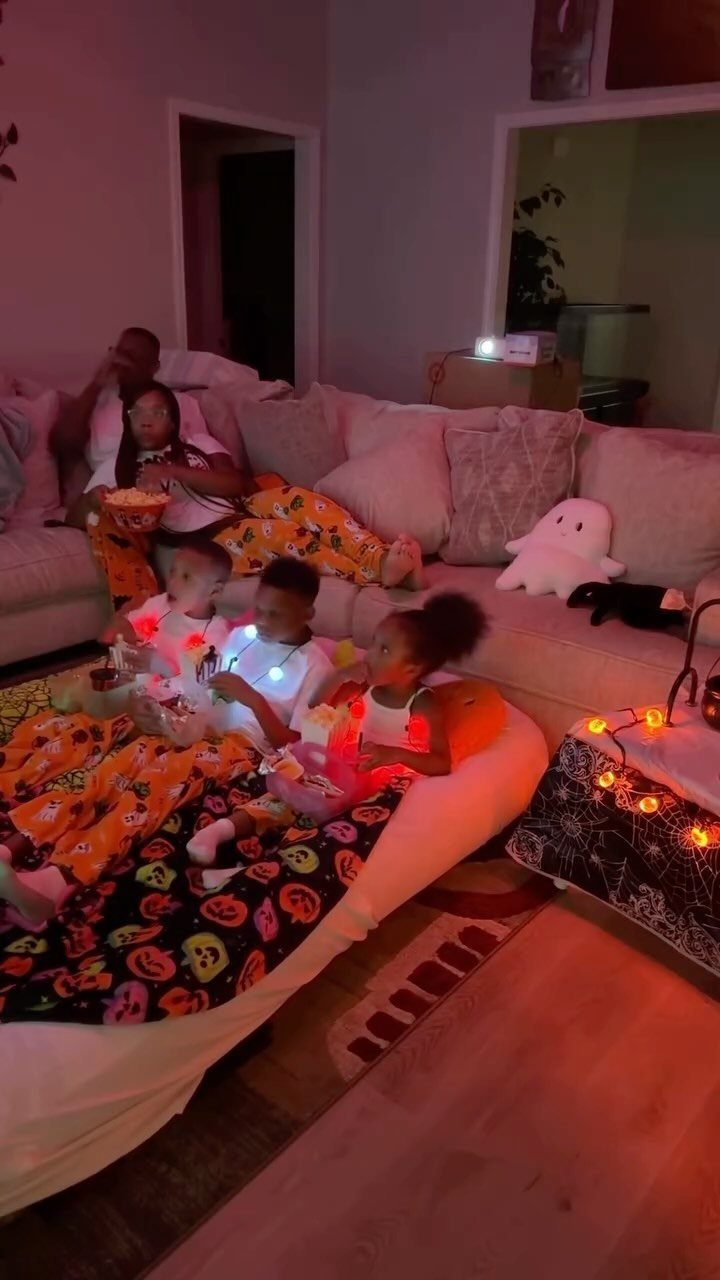 Family in orange pajamas relaxing on a sofa and mattress for movie night.