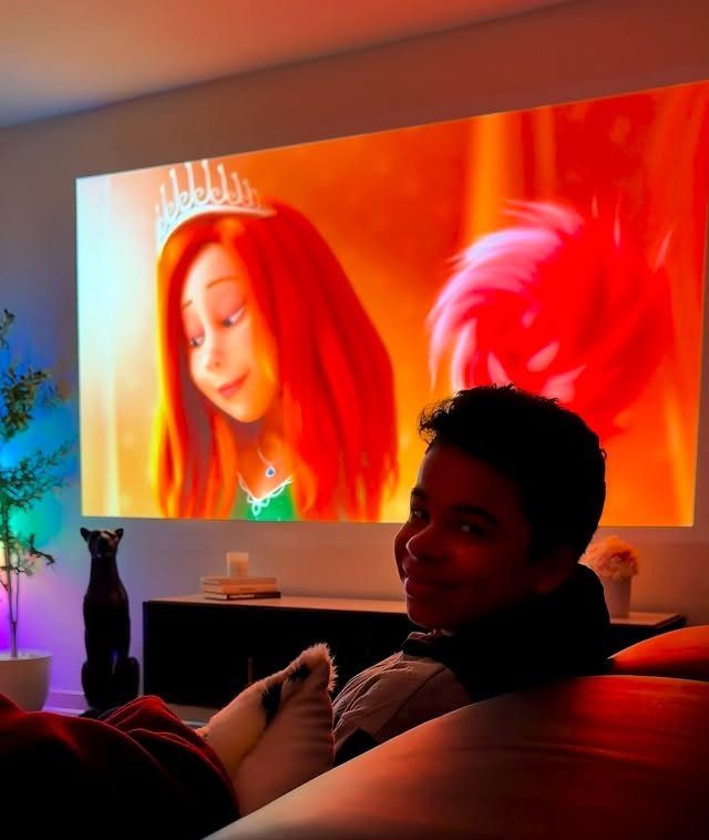 Person relaxing on a couch while an animated movie is projected on the wall