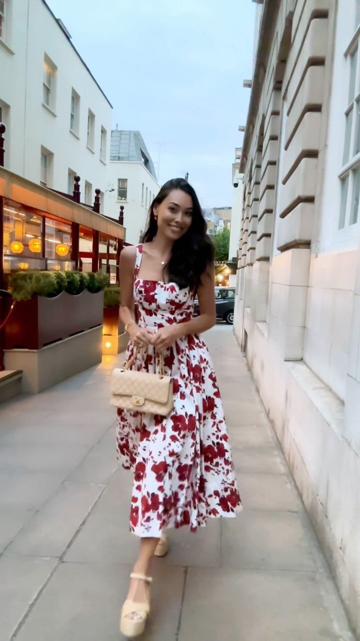 Woman in a red and white floral midi dress posing on a city street