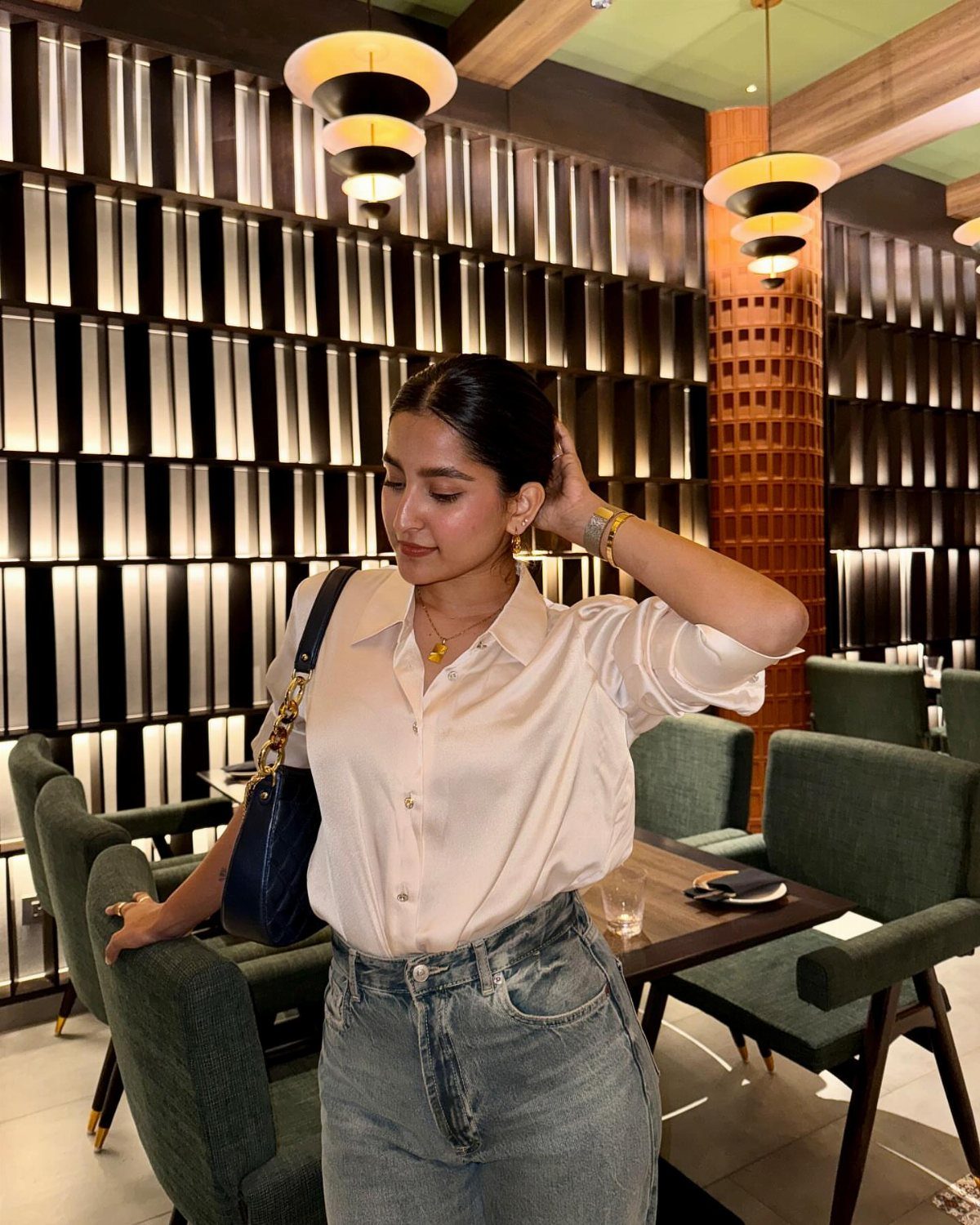 Woman wearing a white silk shirt and light blue jeans in a restaurant