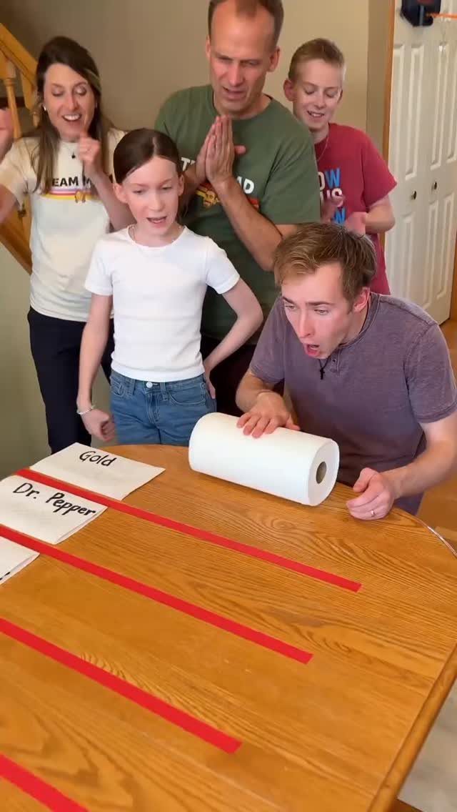 Family reacting with excitement while playing a paper towel racing game on a table