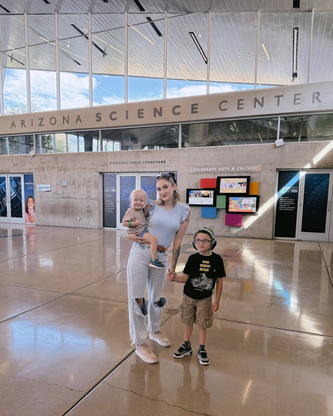 Woman and two children posing inside the Arizona Science Center lobby.