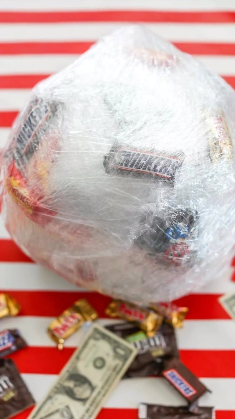 Saran wrap ball filled with candy and prizes on a striped background