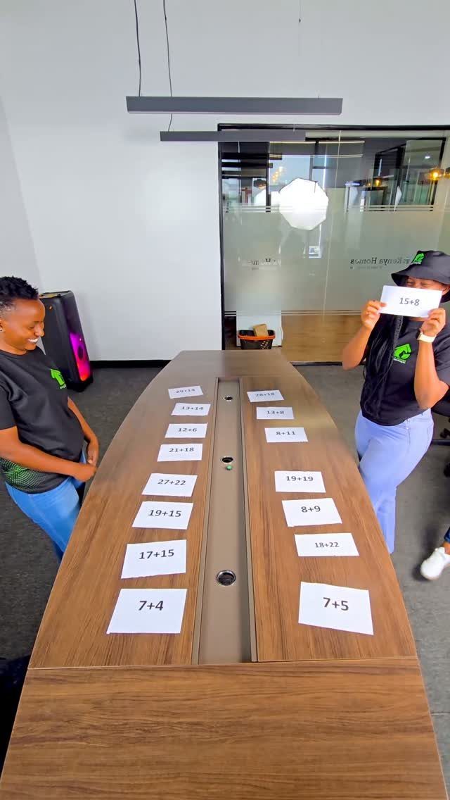Two women playing a math game with slips of paper on a table