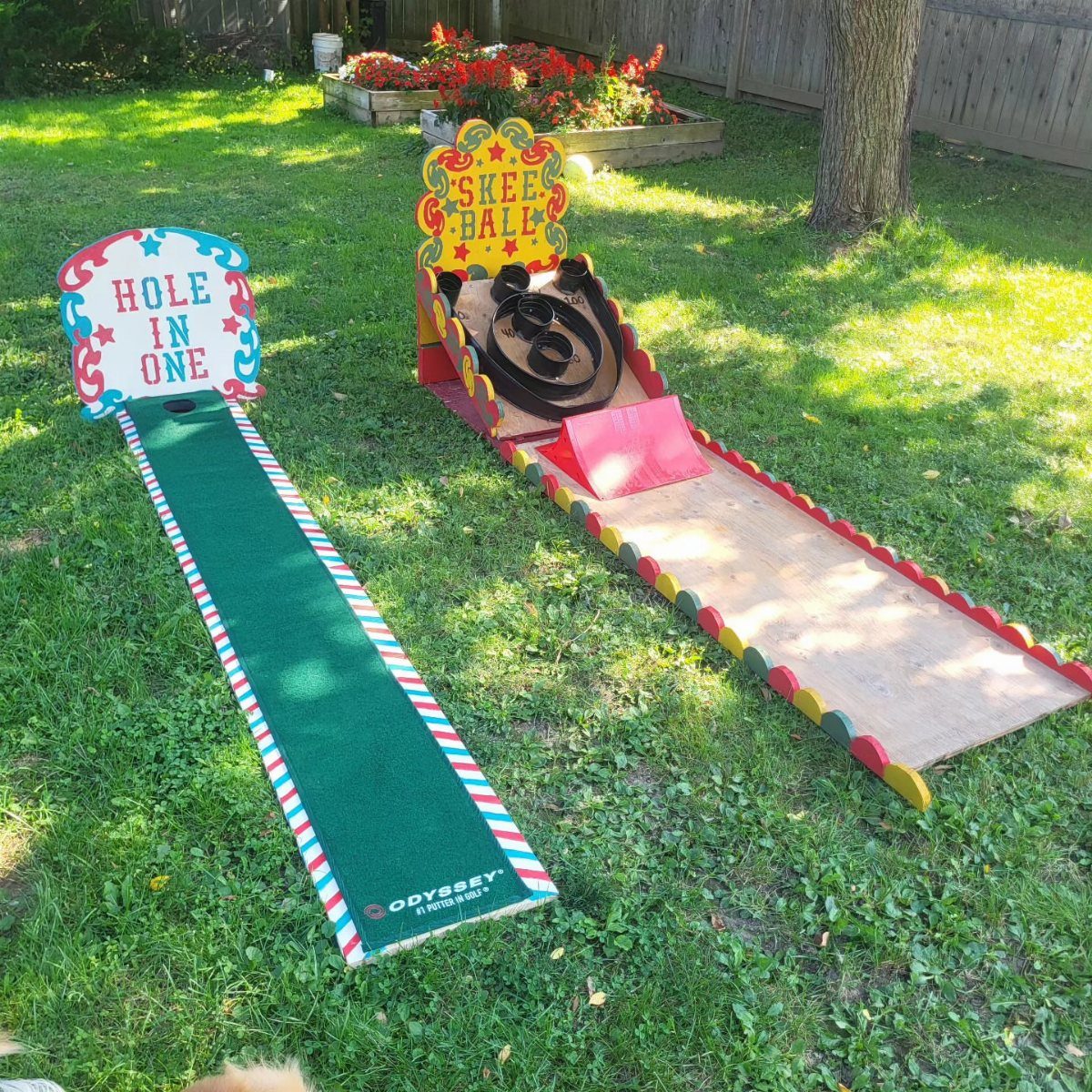 Carnival game setups including a putting green and Skee Ball lane on grass.