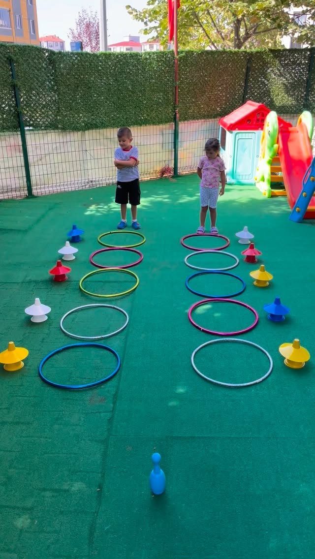 Two children standing at the start of a colorful hoop obstacle course outdoors.