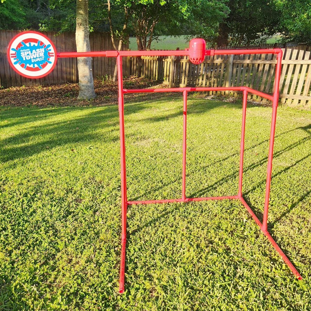 Red metal splash tower game frame standing on a sunny green grass lawn