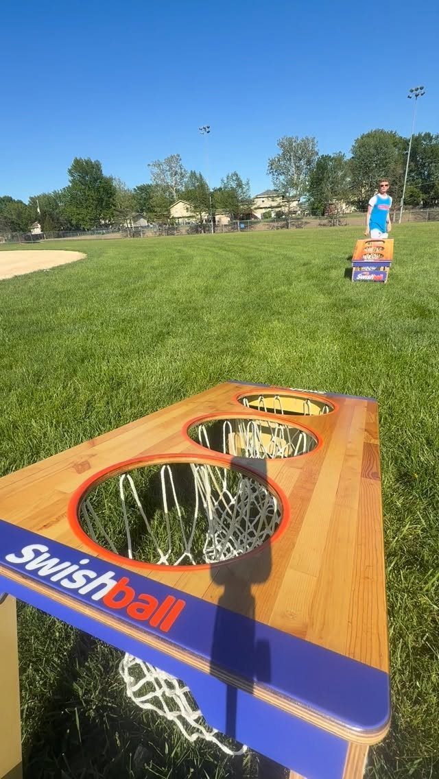 Wooden Swishball game board with nets on a sunny green grass field