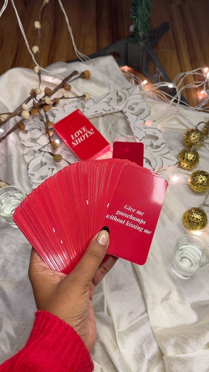 Hand holding red game cards over a white cloth with gold ornaments.