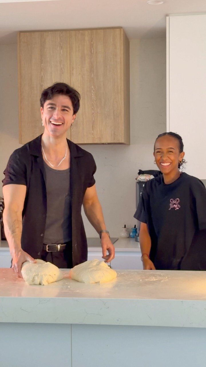 A smiling couple preparing dough together in a modern kitchen for a date.