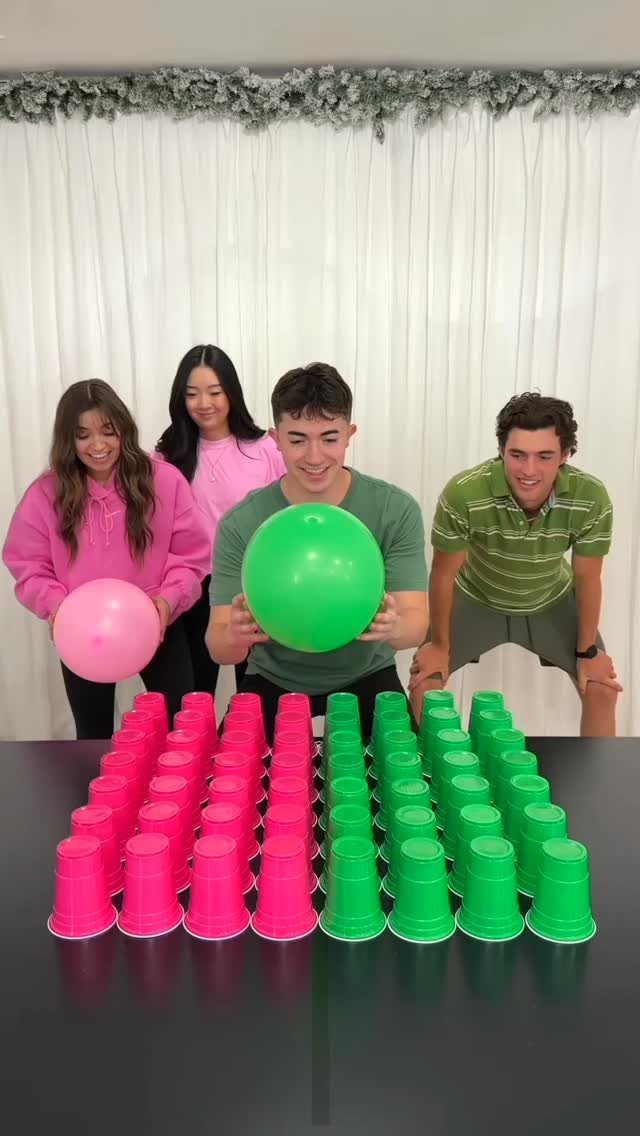 Four young adults preparing to play a game with balloons and plastic cups.