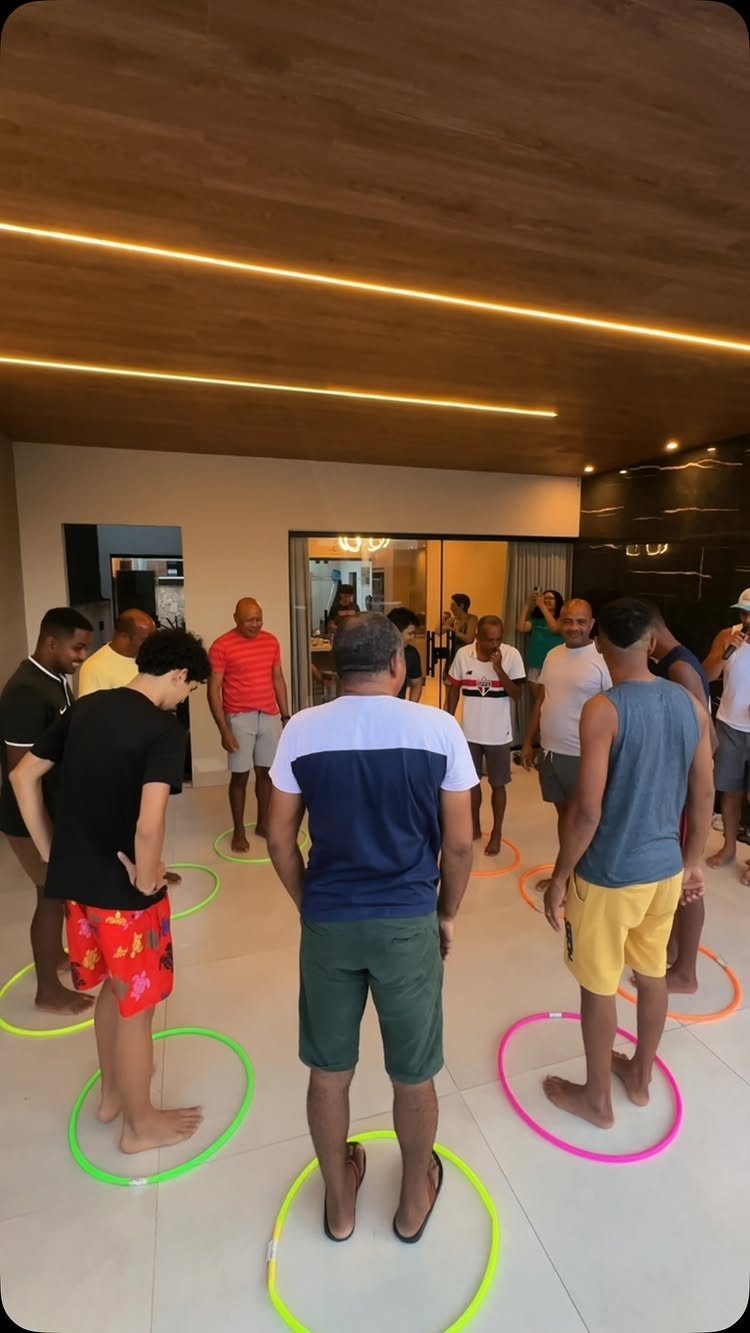 Men standing inside colorful hula hoops on the floor during a party game.