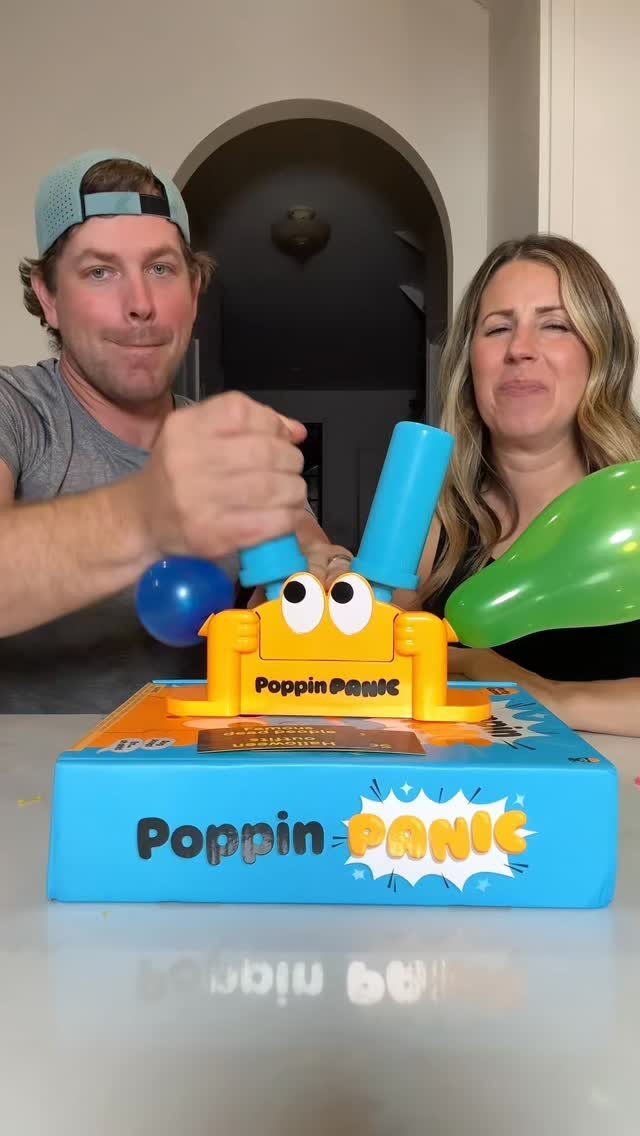 Man and woman playing Poppin Panic board game with colorful balloons popping out.
