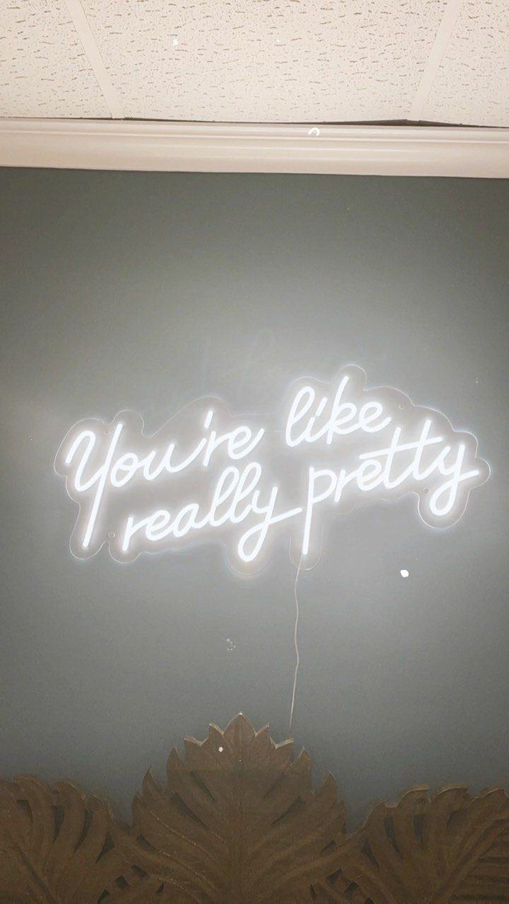 White neon sign reading You're like really pretty on a grey wall