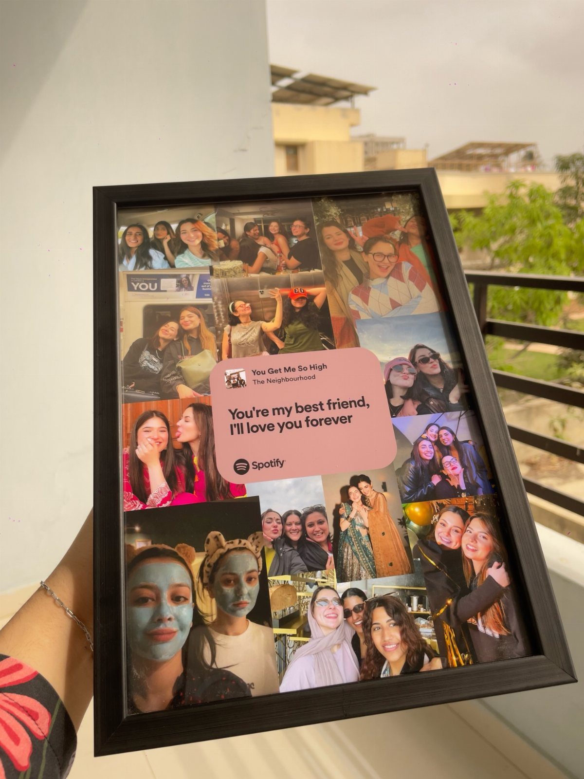 Black picture frame containing a photo collage of friends and a pink music graphic.