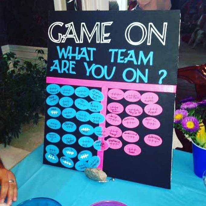 Gender reveal game board with blue and pink football stickers for guest guesses.