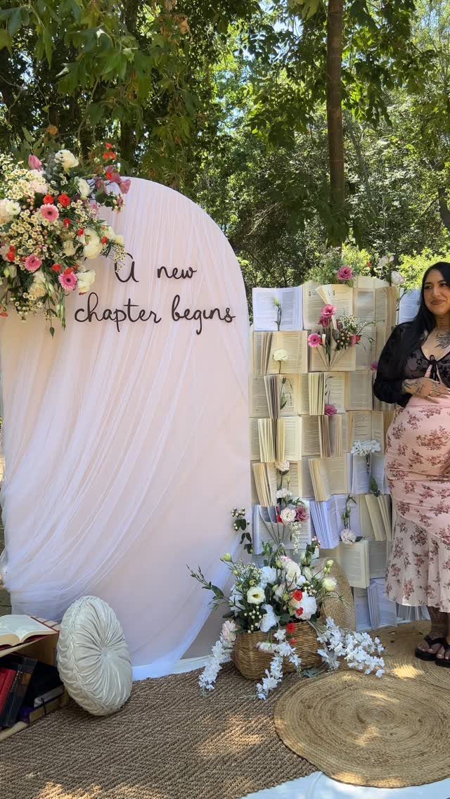 Event backdrop with 'A new chapter begins' text, flowers, and a book wall.