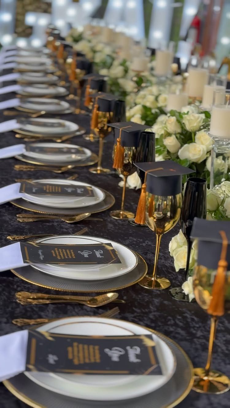 Graduation party table setting with white roses, gold accents, and cap-topped glasses.