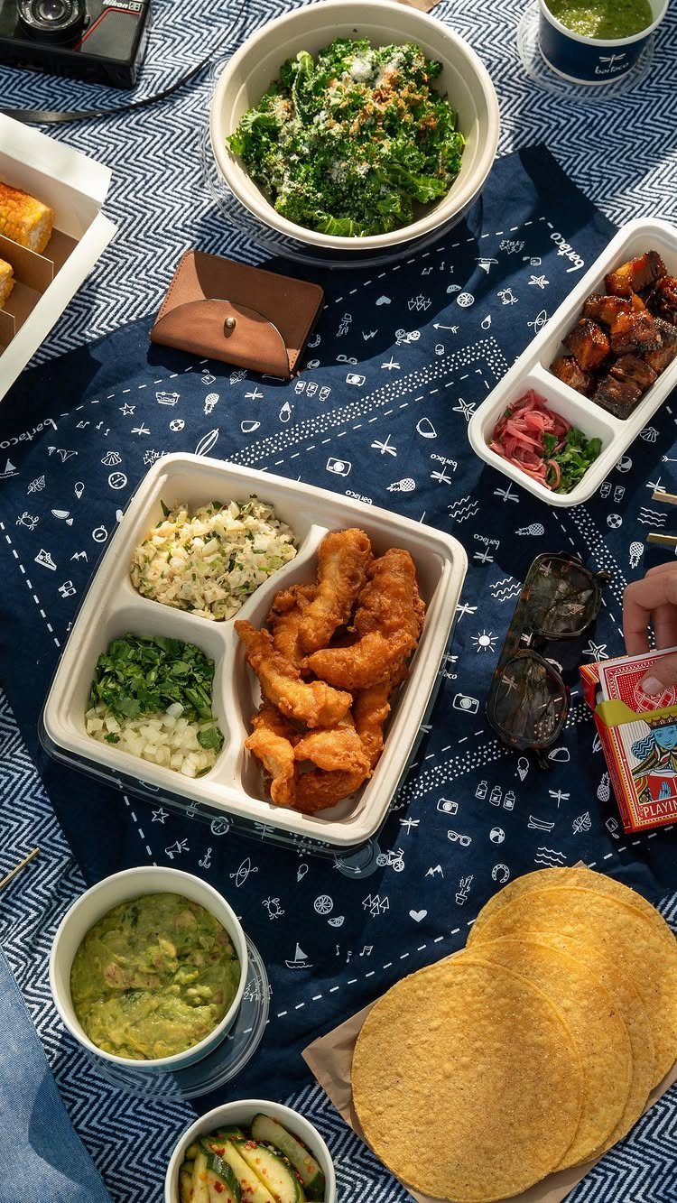 Assorted picnic foods and salads spread on a blue patterned outdoor blanket.