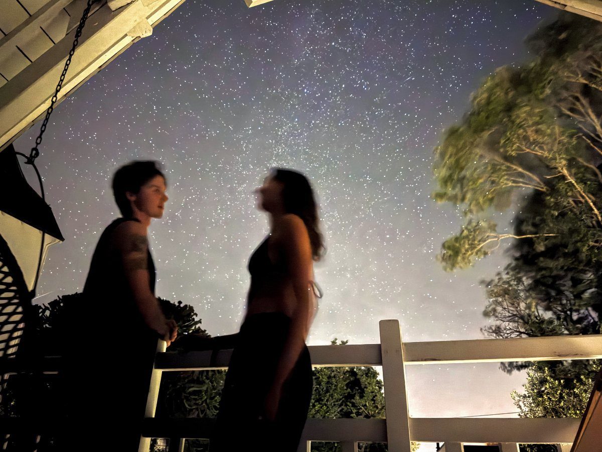 Couple standing on a porch under a starry night sky.