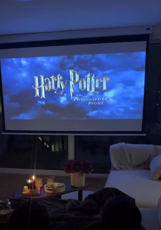 Projector screen showing Harry Potter movie in a cozy living room with snacks.
