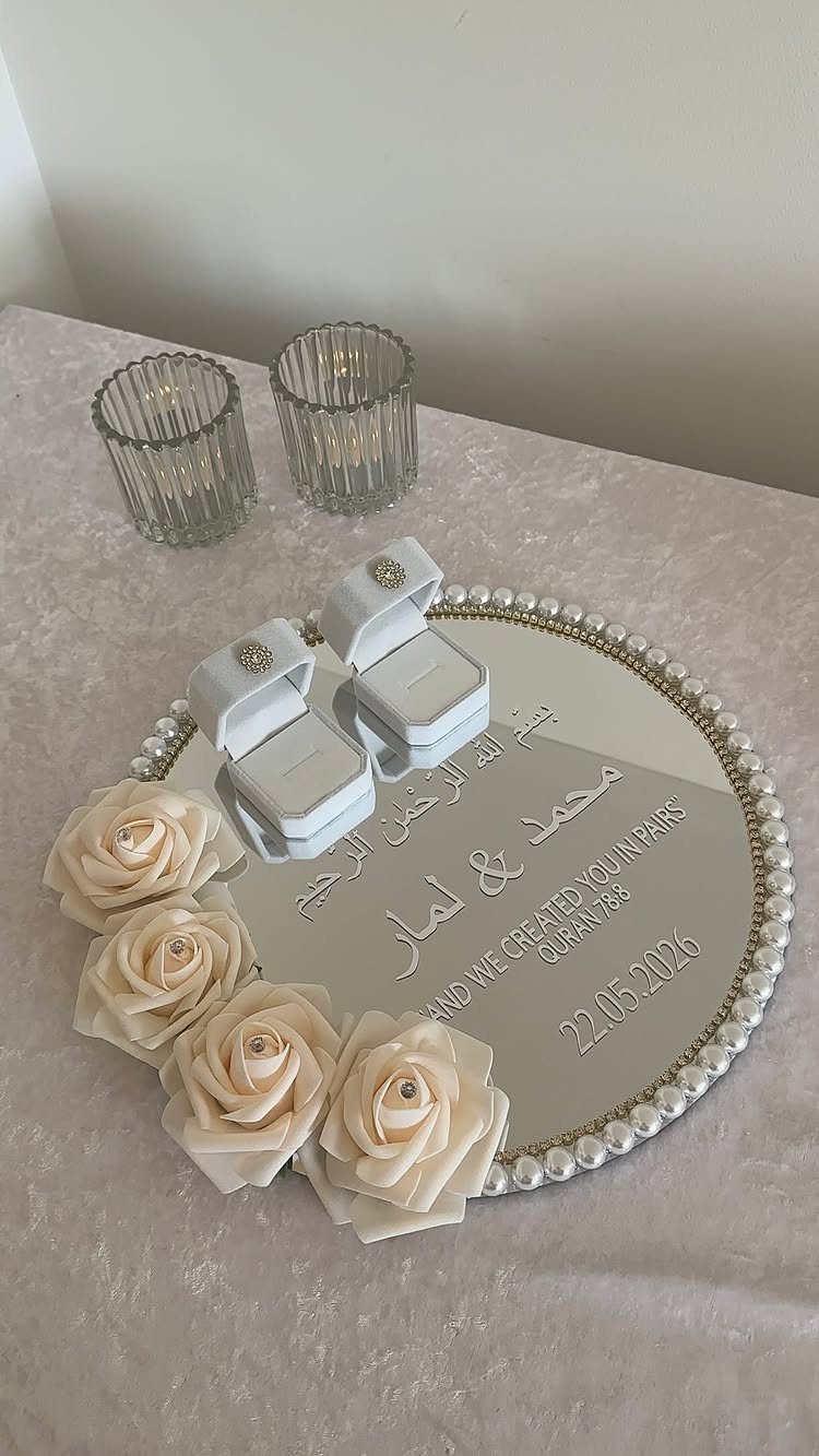 Mirrored tray with pearl edges, white ring boxes, and cream roses for engagement.
