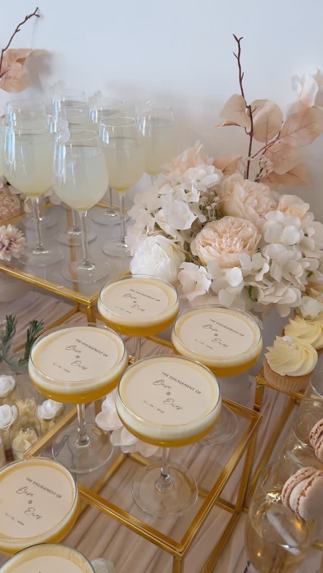Cocktail glasses with foam and personalized text on a gold table with roses.